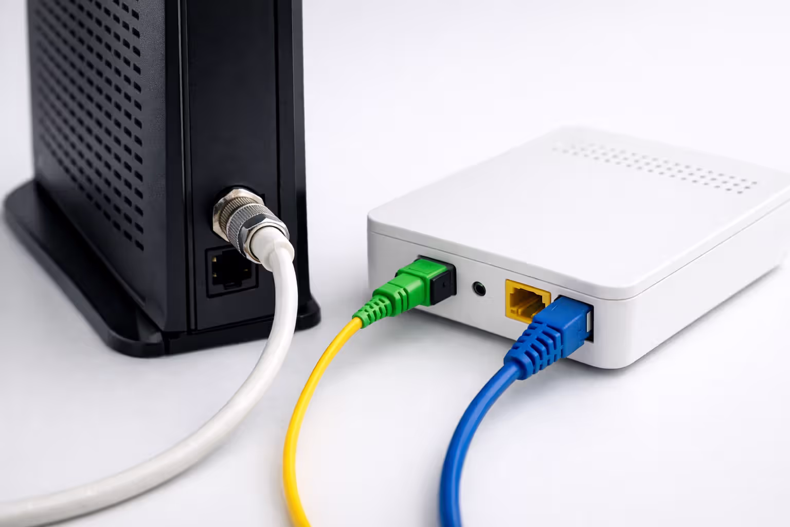Cable modem with coaxial connection next to fiber optic ONT terminal with yellow fiber cable side by side comparison